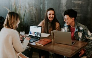 Three millenials sat working in a cafe in the modern workplace
